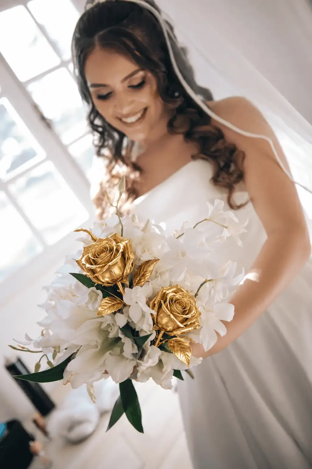 Bride smiling down at her bouquet of gold dipped roses, a gold rose gift gift idea for Düsseldorf, Germany