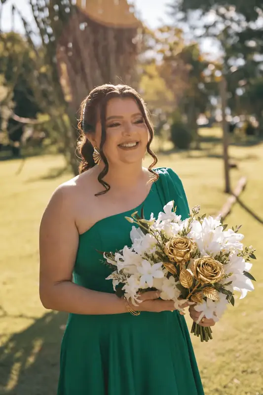 Bridesmaid in a green dress holding a bouquet of gold dipped roses and white flowers, real roses dipped in 24K gold