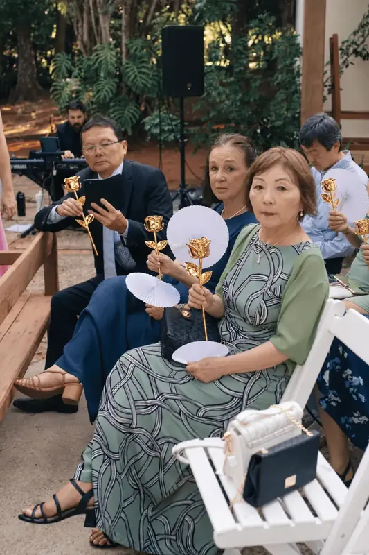 Family of wedding guests holding gold dipped roses and fans, gold dipped rose gift inspiration
