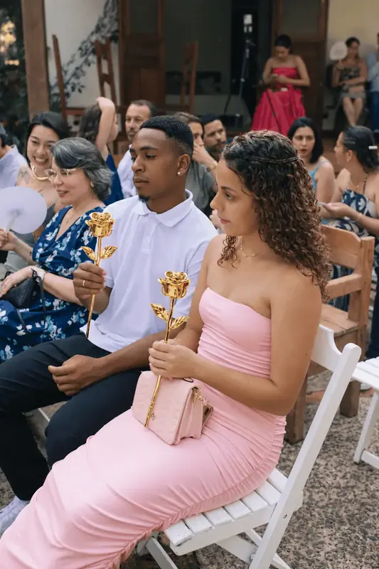 Wedding guests seated at the ceremony holding gold dipped roses, gold rose dome gift ideas for Monaco