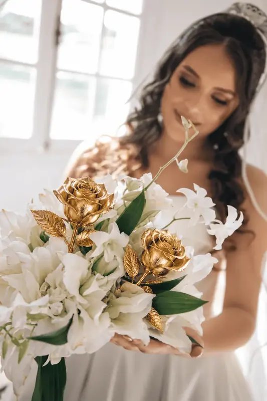 Gold dipped rose close-up: petals sealed in pure 24K gold among white lilies